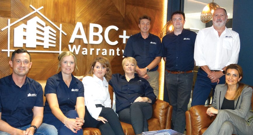 ABC+ Warranty team photo eight members sitting on a couch